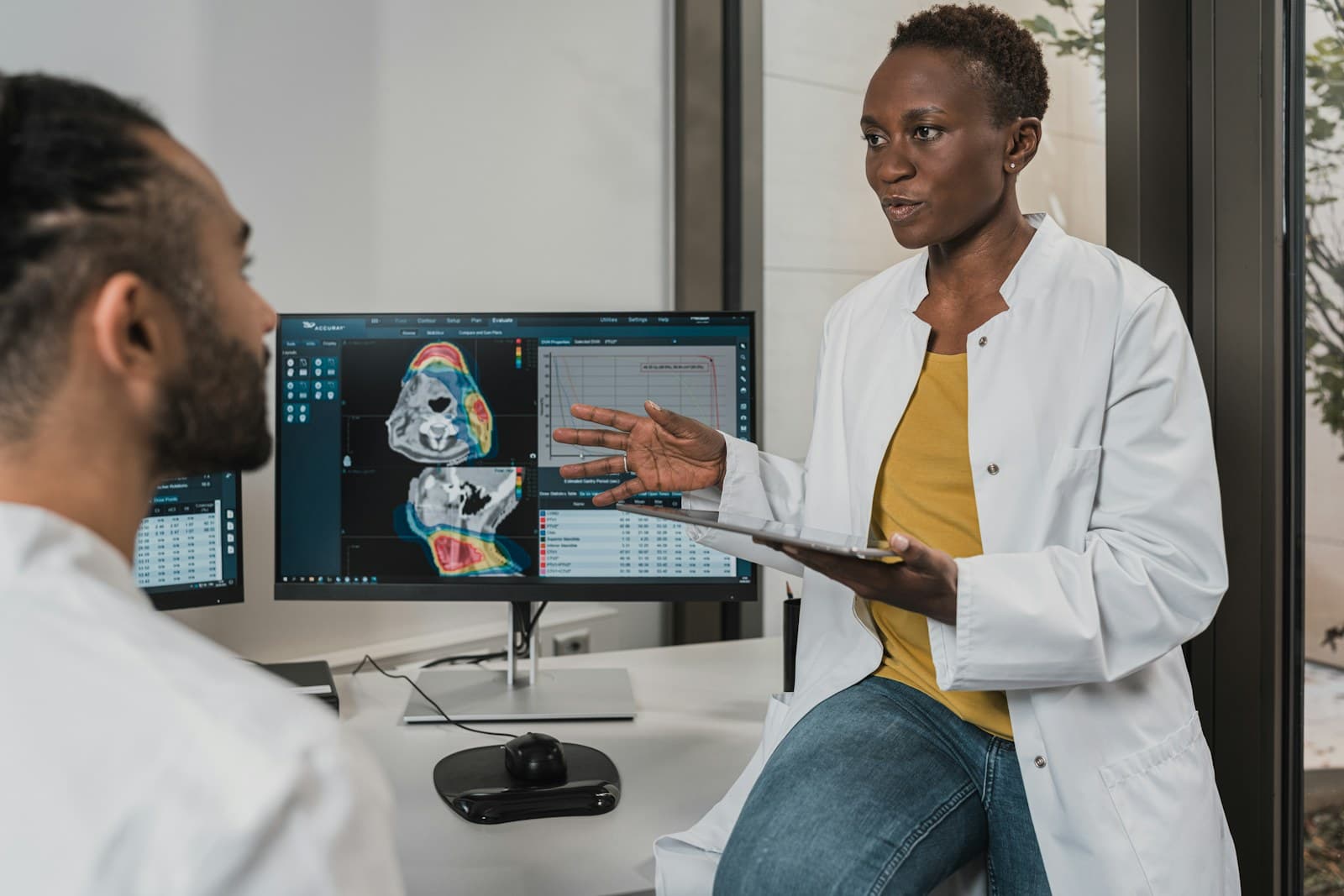 Two clinicians in white coats reviewing medical imaging on a shared display